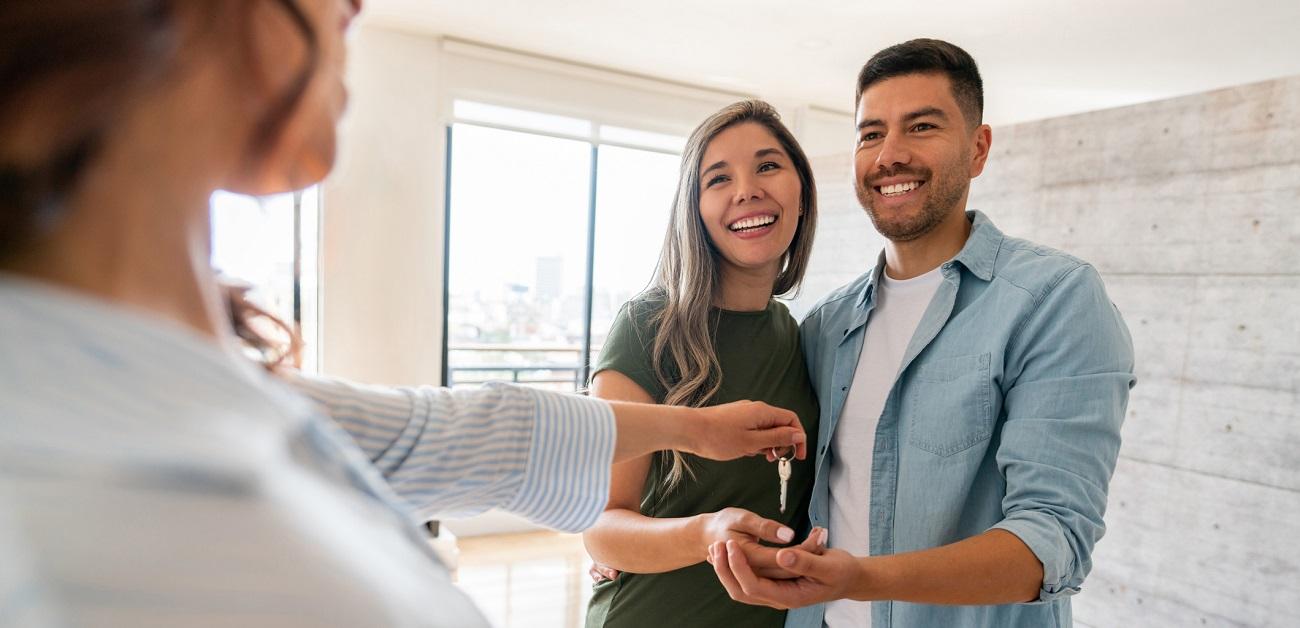 Real estate agent giving keys to a happy couple