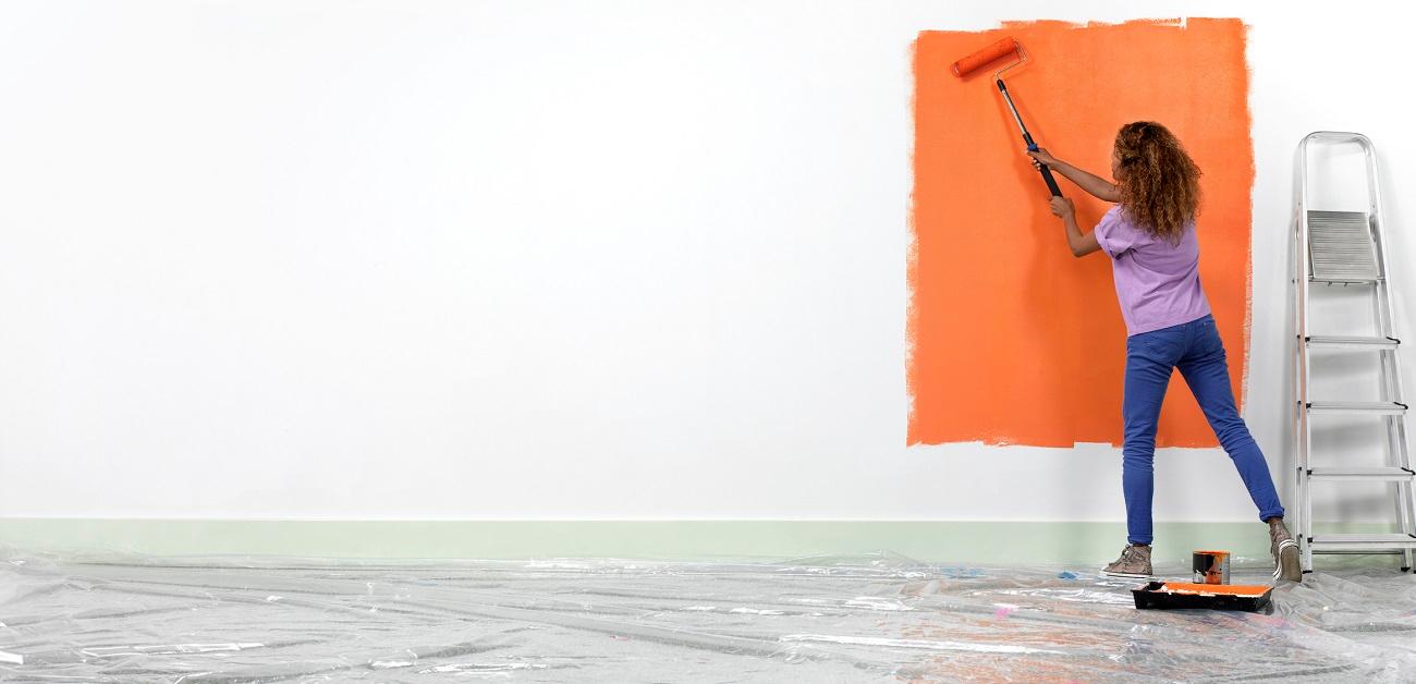 Woman painting a wall orange