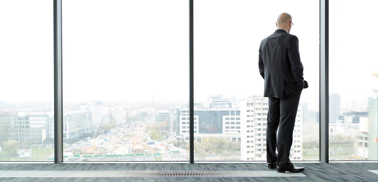 Businessman on empty office floor looking out of window