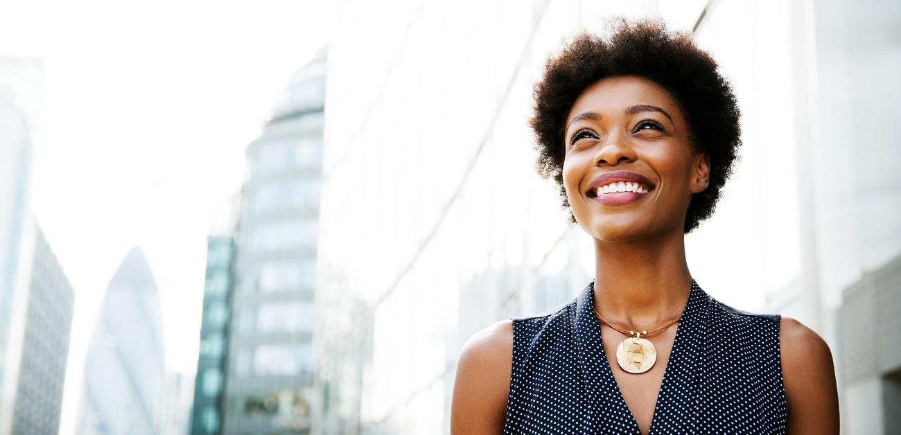 Woman smiling outside next to buildings