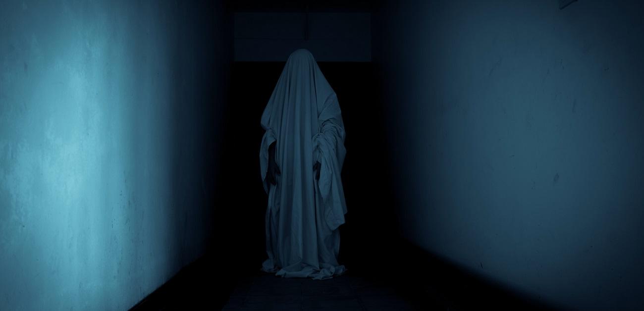 Kid in white sheet dressed up as a ghost for Halloween