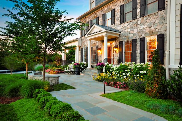 A stone facade house with columned porch and tile walk way.