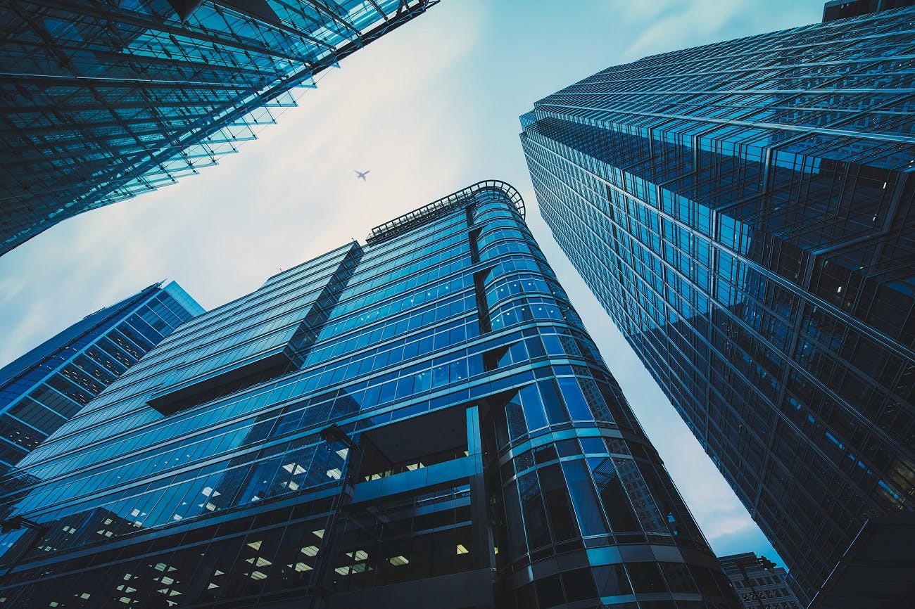 Low angle view of looming multistory glass window commercial office buildings