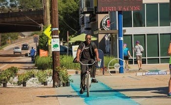 Man riding a bicycle on a bike lane in an urban area