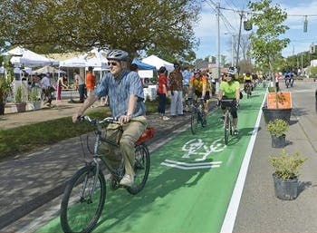 Several people riding their bicycles on a bike lane in an urban area