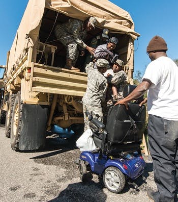 A military officer in a wheelchair being brought down from a truck