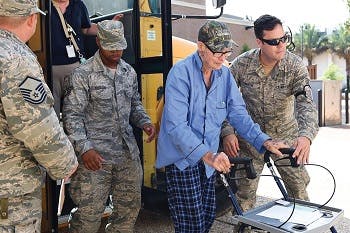 Military officers helping man with a walker