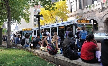 Bus stop in Minneapolis with several people waiting, and other boarding a bus