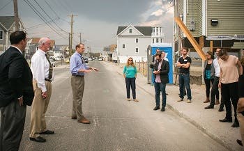 Several people gathered for a meeting while standing on the street in a residential area