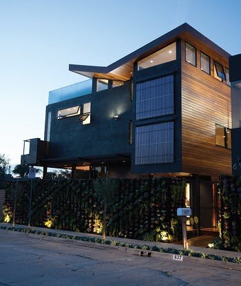 A zero-energy home wood facade with windows featuring metal blinds