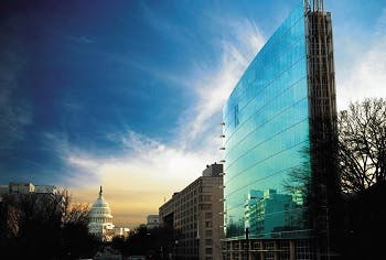 A shot of the DC NAR building and its green glass facade with the Capitol building in the background