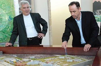 Two men standing up while looking at a city planning map