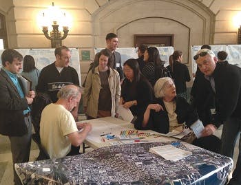 People gathered at a conference near a desk with maps