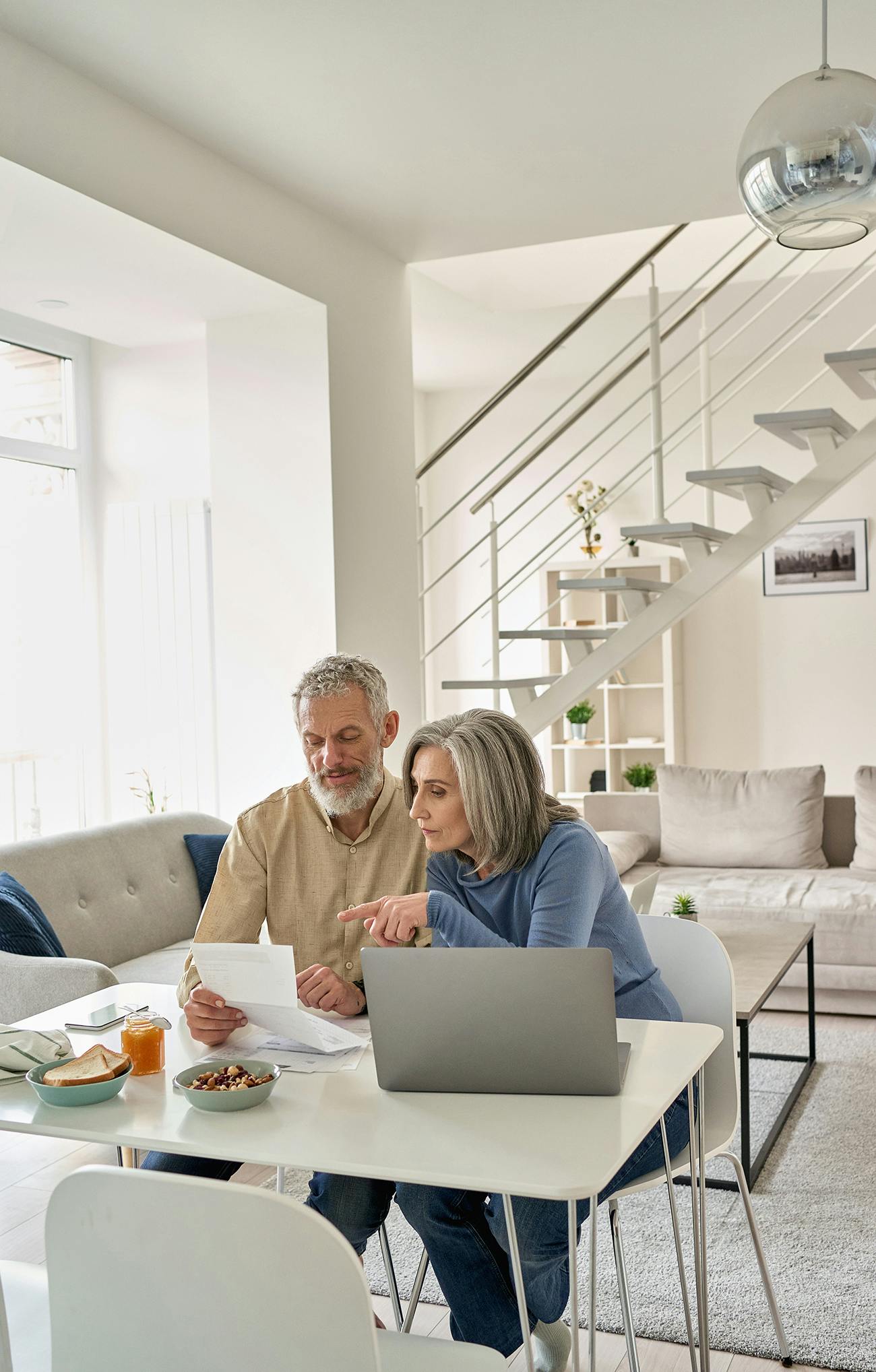 Older couple at a table in their home with laptop and papers