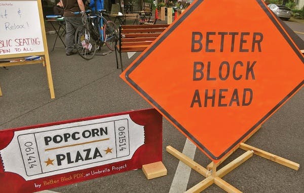 Better Block Ahead sign next to a sign that reads popcorn plaza