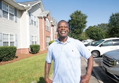 African American man standing in front of apartment building complex