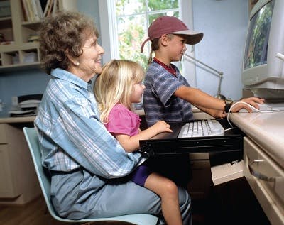 Elderly woman sitting at the computer interacting with her grandkids