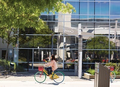 Woman riding bicycle in front of the Google headquarters, Sillicon Valley