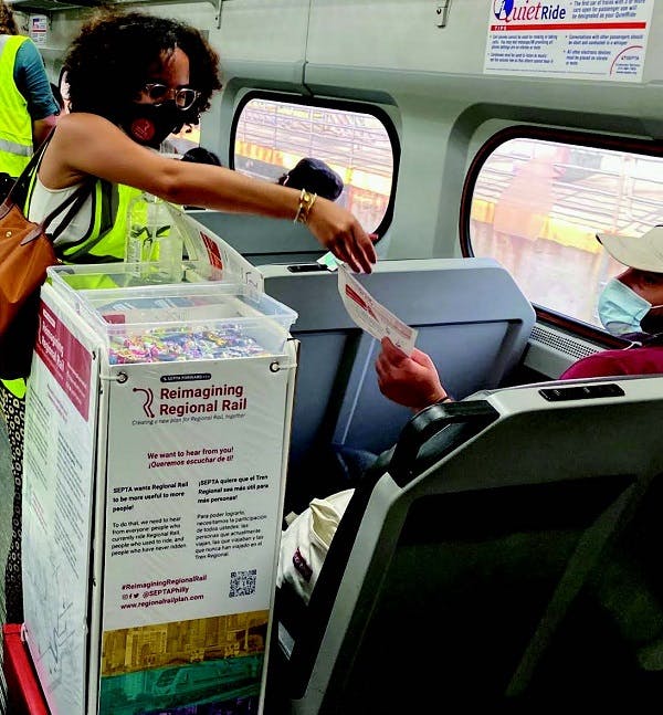 Woman pushing a snack cart in a train in Pennsylvania handing out online survey brochures.