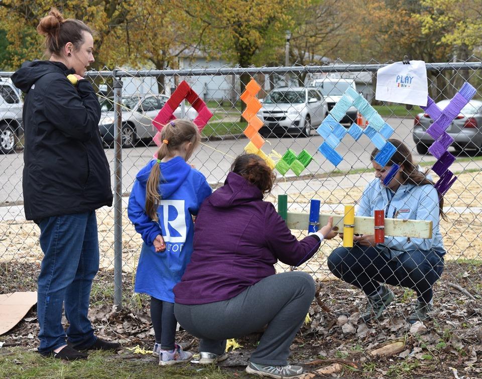 Lansing, MI, Pop-Up Park -girl in blue realtor jacket helping 3 women decorate the park fence