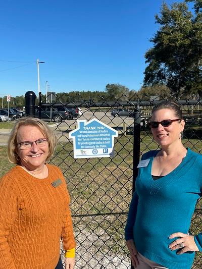 Two women standing next to the plaque commemorating the West Volusia Association of REALTORS®’ contribution to the bike station