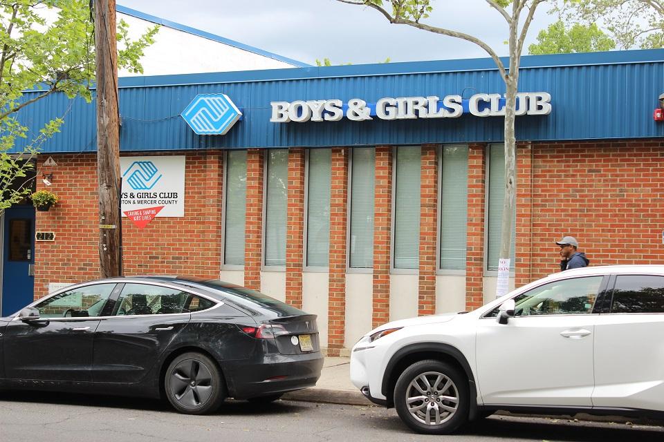 A black and a white car parked right outside the Boys & Girls Club building.