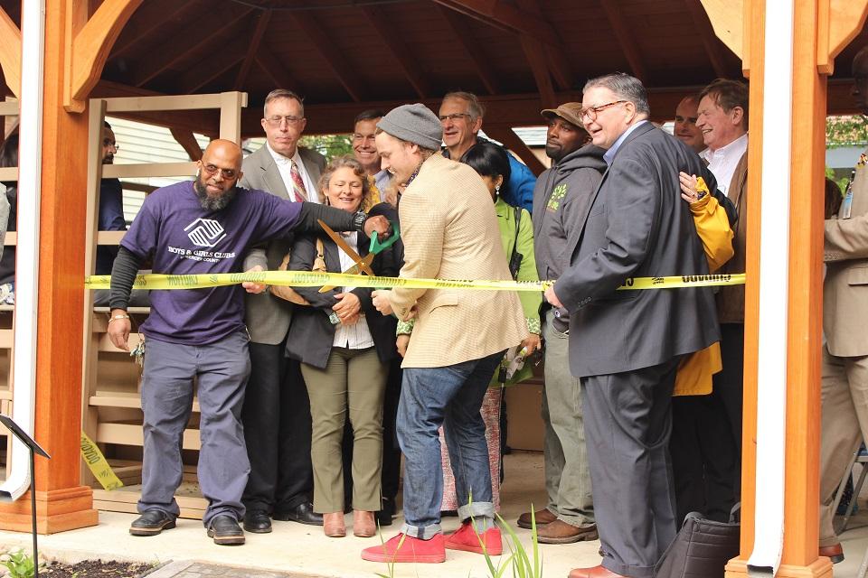 Several people standing inside the pavillion next to a man holding the scissors during the ribbon cutting ceremony.