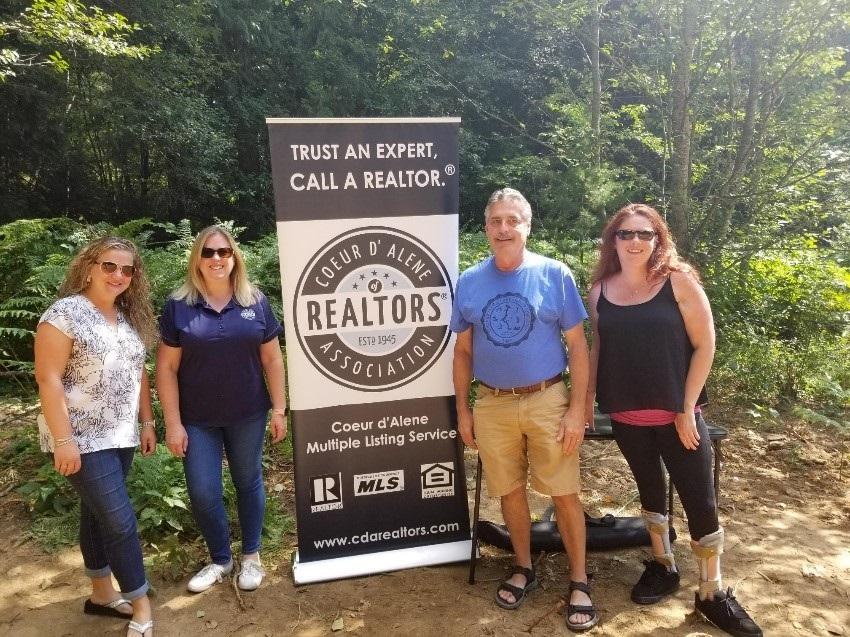 The Mayor of Rathdrum and REALTORS® standing next to a Coeur d’Alene Association of REALTORS® sign 