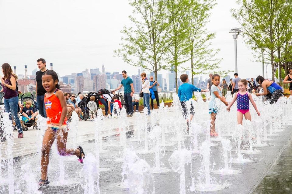 Children running through water jets at Domino Park, Brooklyn, New York