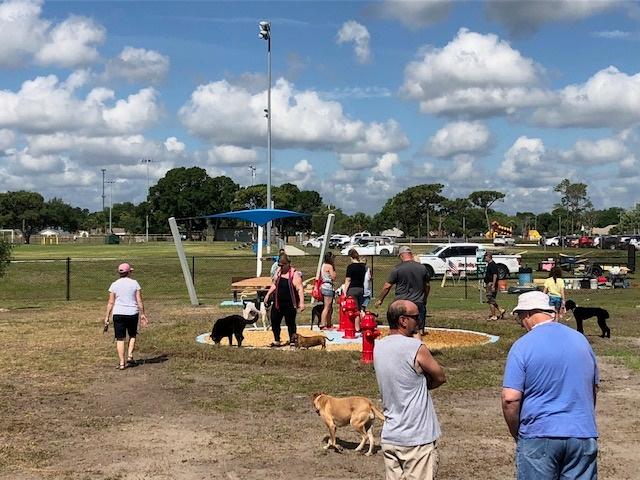 Melbourne, FL dog park - people standing next to painted fire hydrants, covered bench in the background