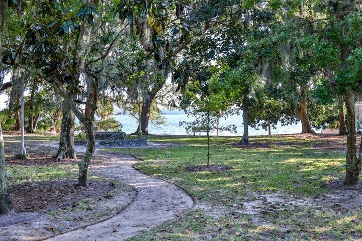 A walking path in Adams Park in Panama City, FL, covered by mud and leaves with the bay in the background