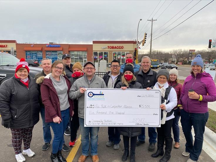 A group of people holding the Saint Paul Area Association of REALTORS®' placemaking grant check for the parking lot welcome sign