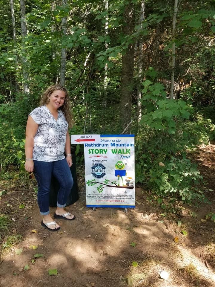 Amanda Kuespert, President of the Coeur d’Alene Association of REALTORS® standing next to a storytrail sign