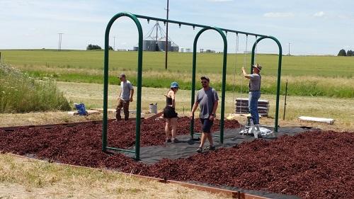 Volunteers installing wood chips around playground equipment at the Viola Community Center, ID