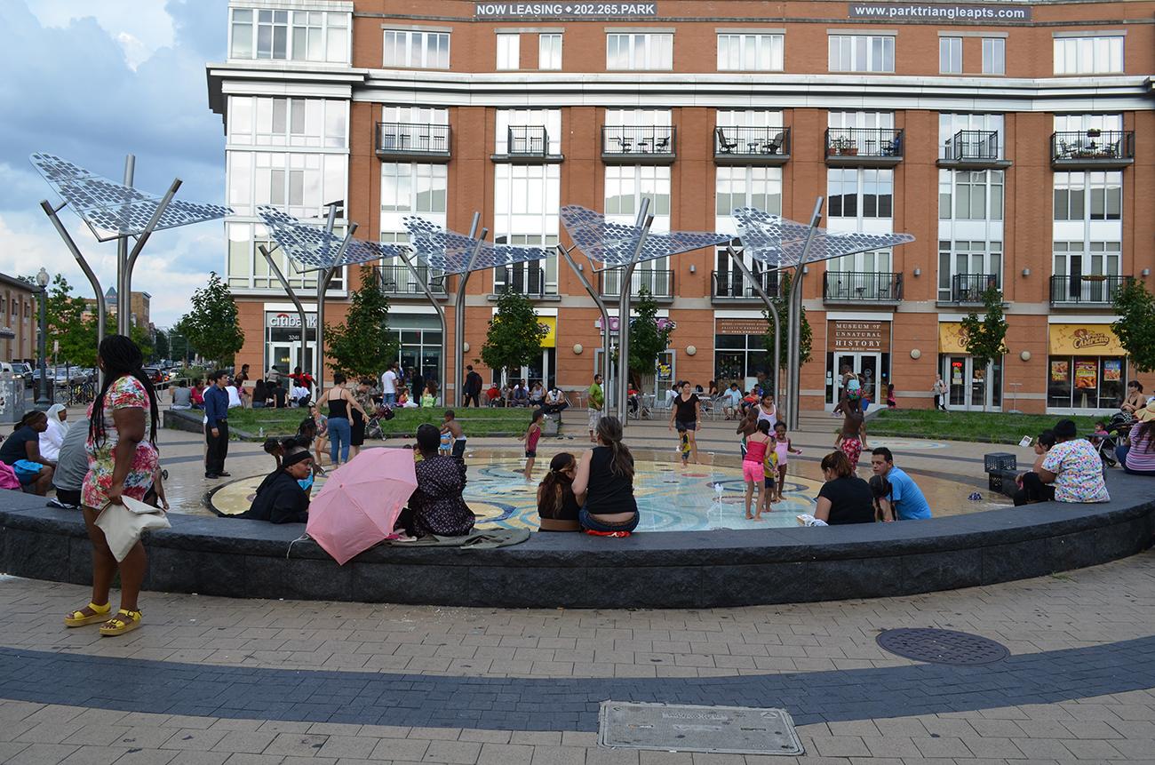 People sitting around a fountain at Columbia Heights Plaza in Washington, DC