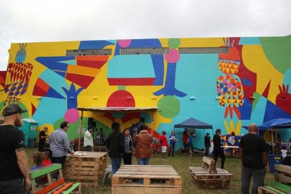 People setting up tents and places to sit in front of a mural