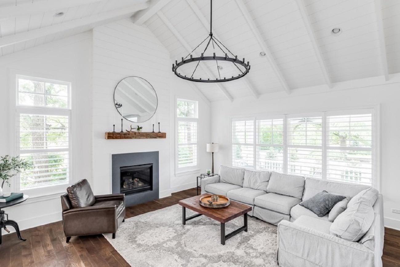 Farmhouse style living room space with fireplace, chandelier, vaulted ceilings