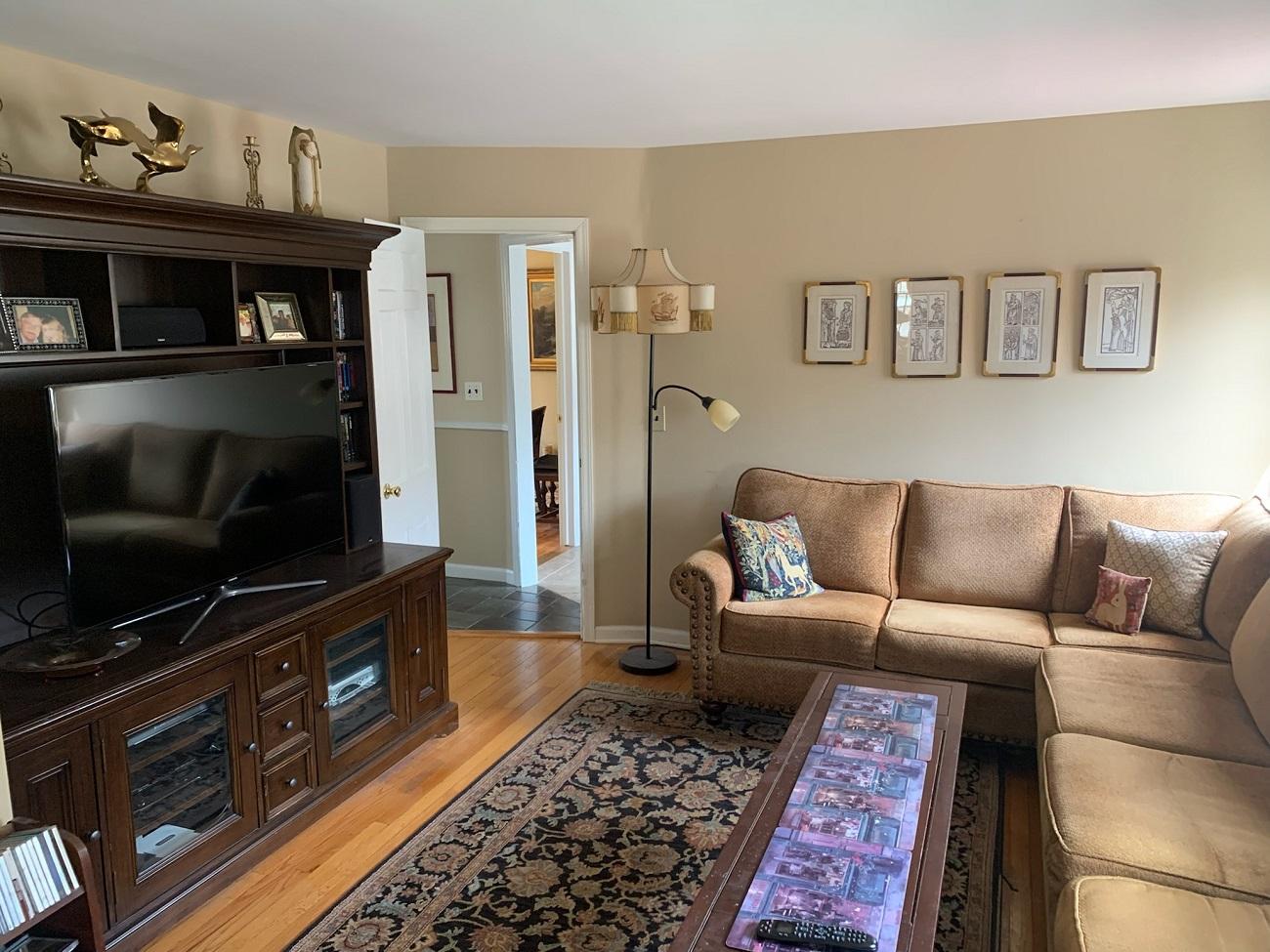 A living room space with cream colored walls and dark furnishings before being redesigned and staged into a dining room