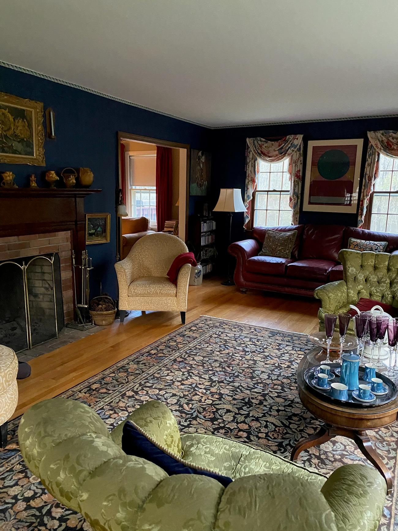 A living room space with dark blue walls and dark furnishings before being redesigned and staged