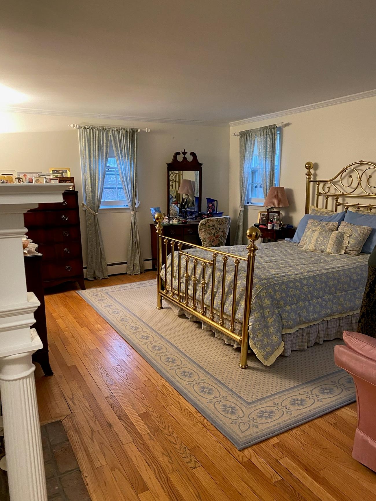 A primary bedroom full of furniture before being redesigned and staged