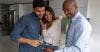 Real estate agent and clients standing in kitchen looking at tablet