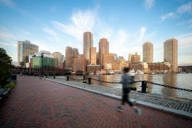 Woman running near Boston Harbor at sunrise