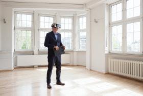 Business man in an empty room with virtual reality mask on