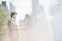 Business man and woman shaking hands outdoors