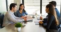 Young couple signing real estate contract in broker's office with a pair of agents