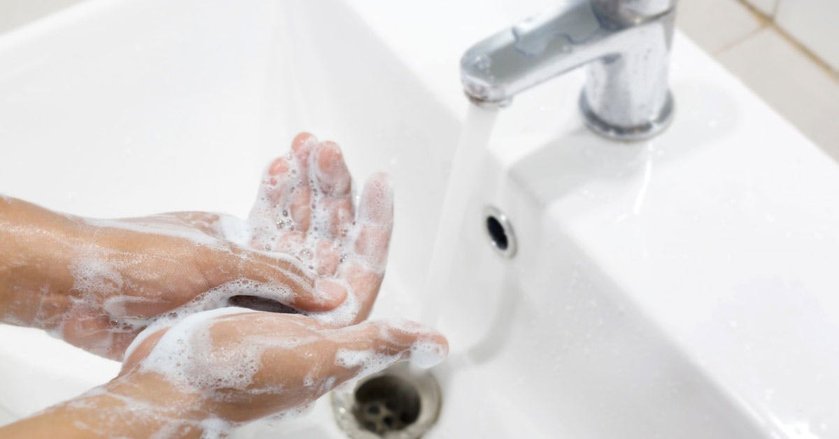 Adult washing hands in white sink