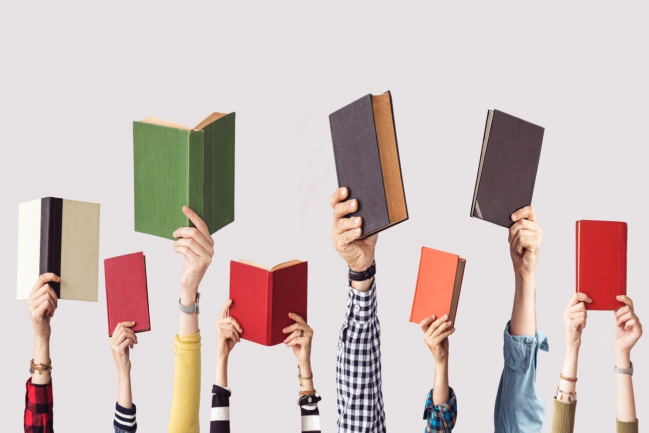 a bunch of hands holding up different colored books