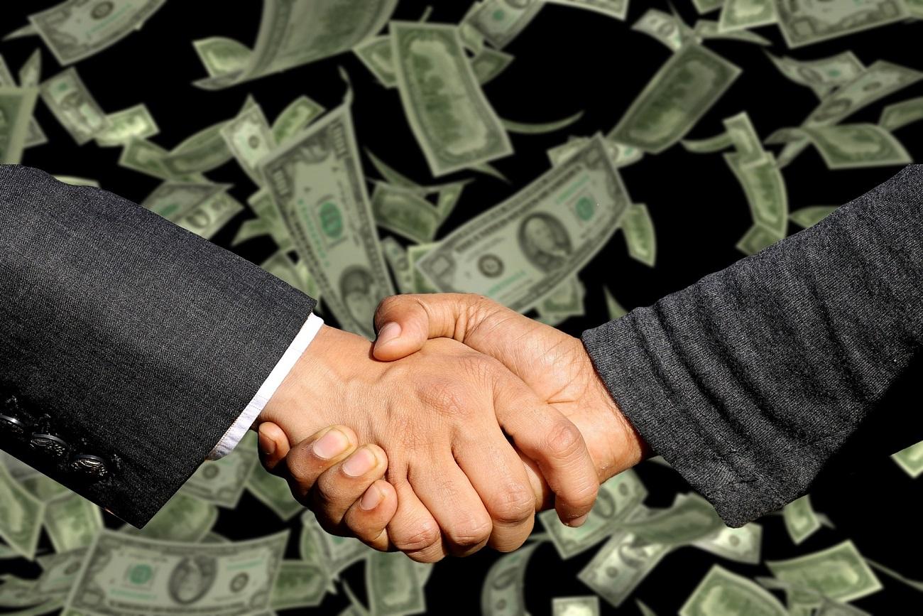 businessmen shaking hands with money in the background