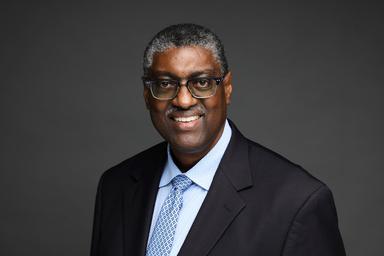 Headshot of a middle age Black man wearing a black suit with a light blue tie