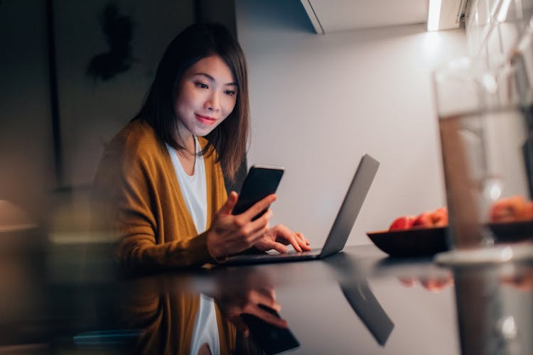 RAE Winter 2021 business woman checking cell phone with laptop